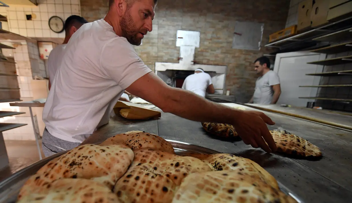 Pekerja membuat somun di sebuah toko roti di kota tua Sarajevo, Bosnia and Herzegovina, Kamis (30/4/2020). Roti somun lebih nikmat disantap selagi hangat saat berbuka puasa atau sahur. (ELVIS BARUKCIC/AFP)