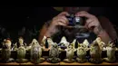 Seorang pengunjung memfoto model katak yang menggambarkan sedang menghadiri jamuan makan malam yang dipamerkan di Museum Katak di Estavayer-le-Lac, Swiss barat (22/6). (AFP Photo/Fabrice Coffrini)