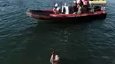Seorang perenang memegang sebuah salib kayu yang dilemparkan ke laut saat restu upacara air menandai hari Epiphany Orthodox, di pelabuhan Thessaloniki, Yunani utara, (6/1). (AFP Photo/Sakis Mitrolidis)