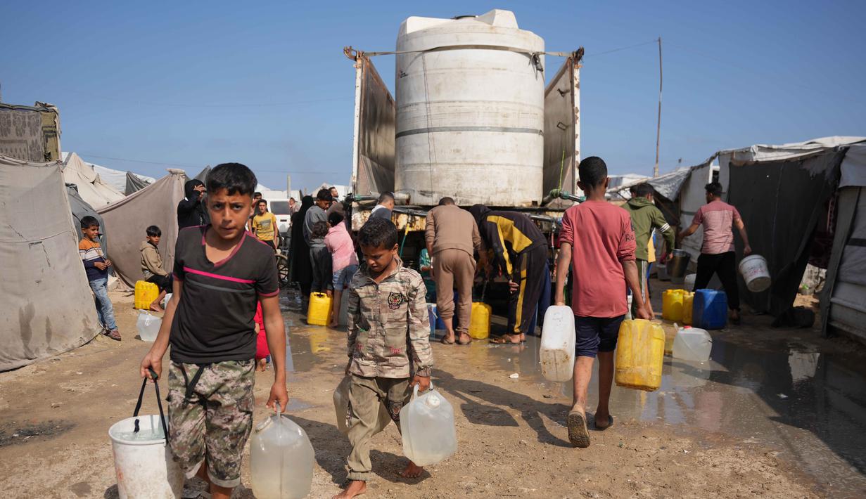 Para pengungsi Palestina berkumpul untuk mengambil air dari sebuah truk di kamp tenda darurat, Khan Younis, Jalur Gaza Selatan, Kamis 30 April 2026. Pengungsi Palestina di kamp-kamp pengungsian darurat di Khan Younis, Jalur Gaza Selatan masih menghadapi krisis air bersih yang parah. (AP Photo/Abdel Kareem Hana)