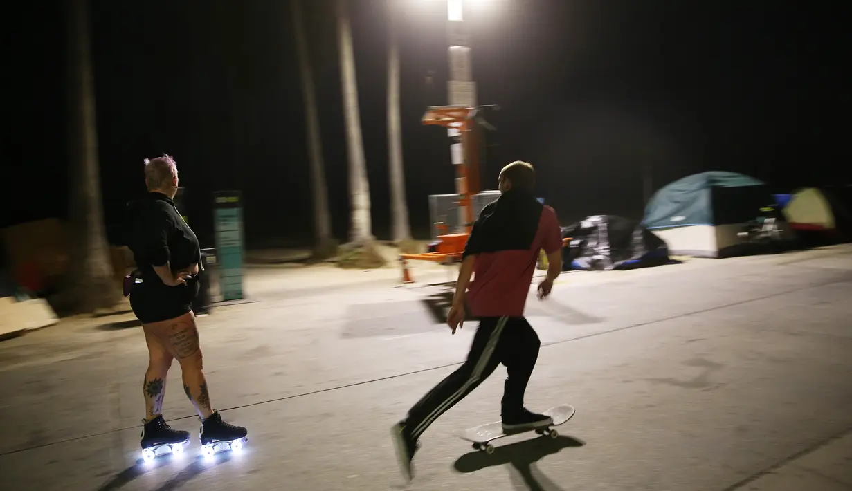 Seorang perempuan bermain sepatu roda di sepanjang trotoar Venice Beach di Venice, California, Kamis (3/9/2020). Menurut data Google, pencarian terkait sepatu roda dari Maret hingga Mei di Amerika Serikat meningkat hampir empat kali lipat. (Mario Tama/Getty Images/AFP)