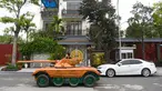 Truong Van Dao melewati sebuah rumah dengan tank kayu di daerah perumahan di provinsi Bac Ninh pada 28 Maret 2022. Seorang ayah di Vietnam telah menghabiskan ratusan jam dan menginvestasikan uangnya untuk mengubah mobil van tua menjadi tank kayu untuk putranya. (Nhac NGUYEN /AFP)