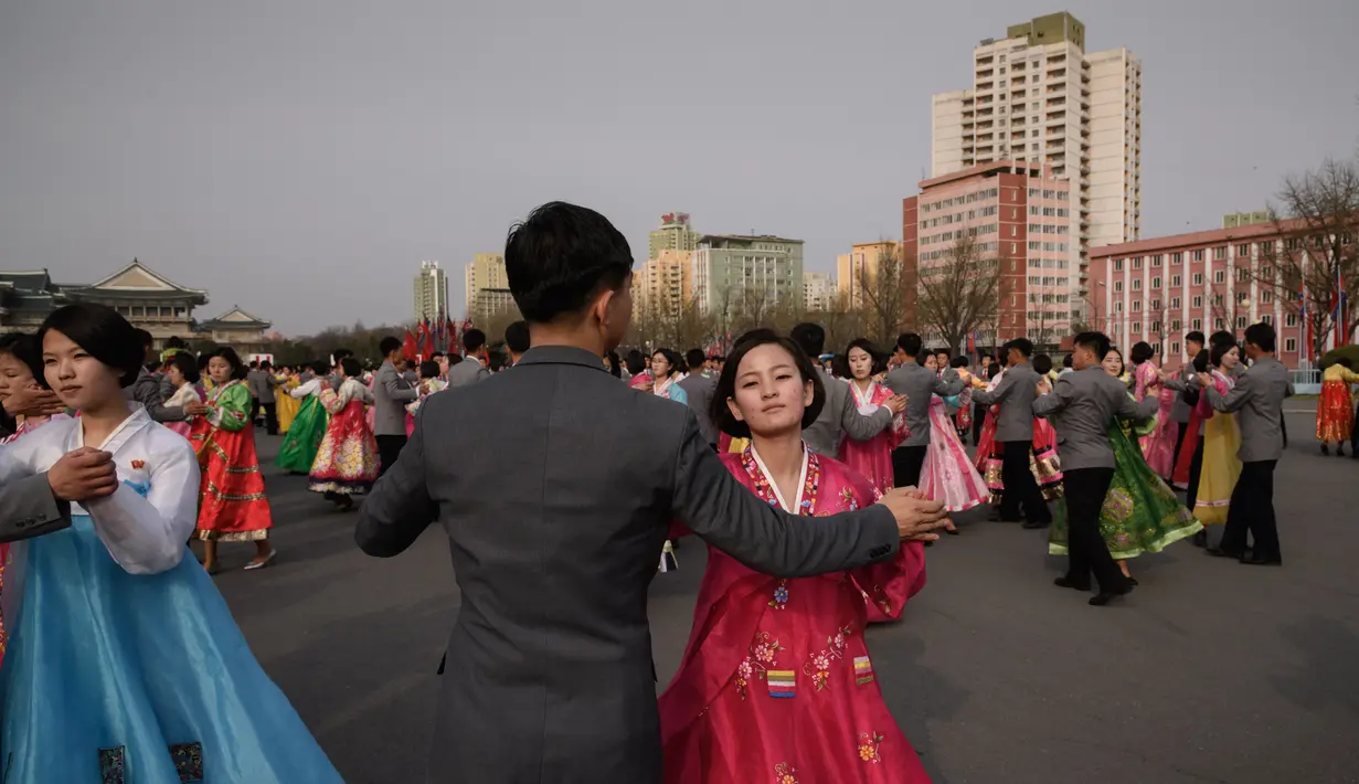 Sejumlah siswa berpasang-pasangan melakukan tarian massal di luar Stadion Indoor Pyongyang, Korea Utara (9/4). Kim Jong Il sendiri merupakan ayah dari Kim Jong-un yang telah menjabat sebagai pemimpin Korea Utara (Korut) sejak 1994. (AFP Photo/Ed Jones)
