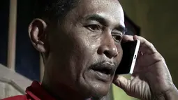 Bapak Sumarti Ningsih, Ahmad Kaliman berbincang lewat ponsel mengenai sidang pembunuhan anaknya di Cilacap, Jawa Tengah , Indonesia (8/11). Rurik Jutting telah dinyatakan dijatuhi hukuman penjara seumur hidup. (REUTERS/Idhad Zakaria)