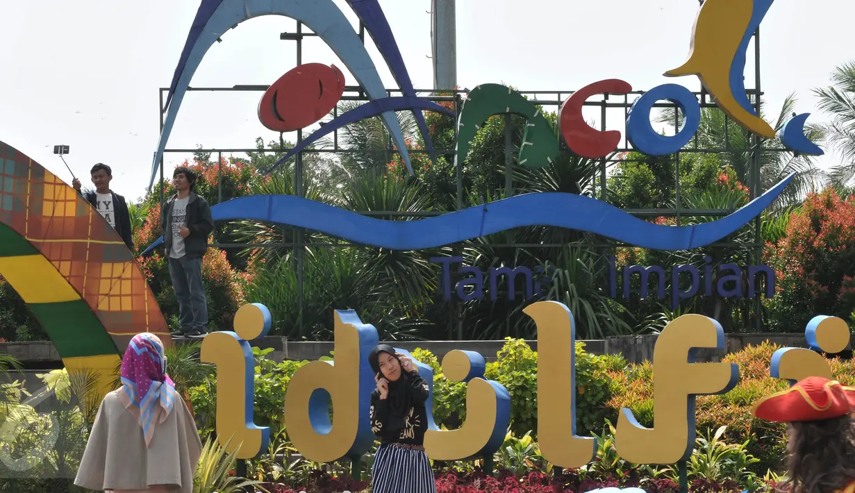 Pengunjung berfoto di depan tulisan Ancol saat berwisata ke Taman Impian Jaya Ancol, Jakarta, Kamis (7/7). Ancol tetap menjadi primadona tempat wisata bagi warga Jakarta dan sekitar untuk mengisi libur Lebaran. (Liputan6.com/Johan Tallo)