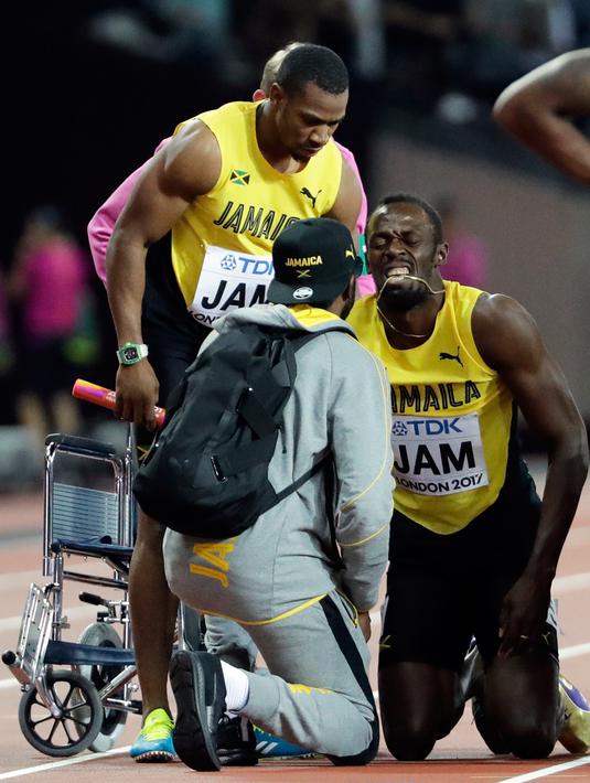 Pelari Jamaika, Usain Bolt mendapat perawatan usai terjatuh karena cedera di final 4x100 meter pada Kejuaraan Dunia Atletik, Sabtu (12/8). Pemegang rekor pelari tercepat di dunia itu terkapar di lintasan dan gagal melanjutkan lomba. (AP/David J. Phillip)