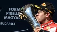 Pebalap Ferrari, Sebastian Vettel, mencium trofi juara F1 GP Seri Hungaria di Sirkuit Hungaroring, Budapest, Hungaria. (26/7/2015). (AFP PHOTO/Andrej Isakovic)