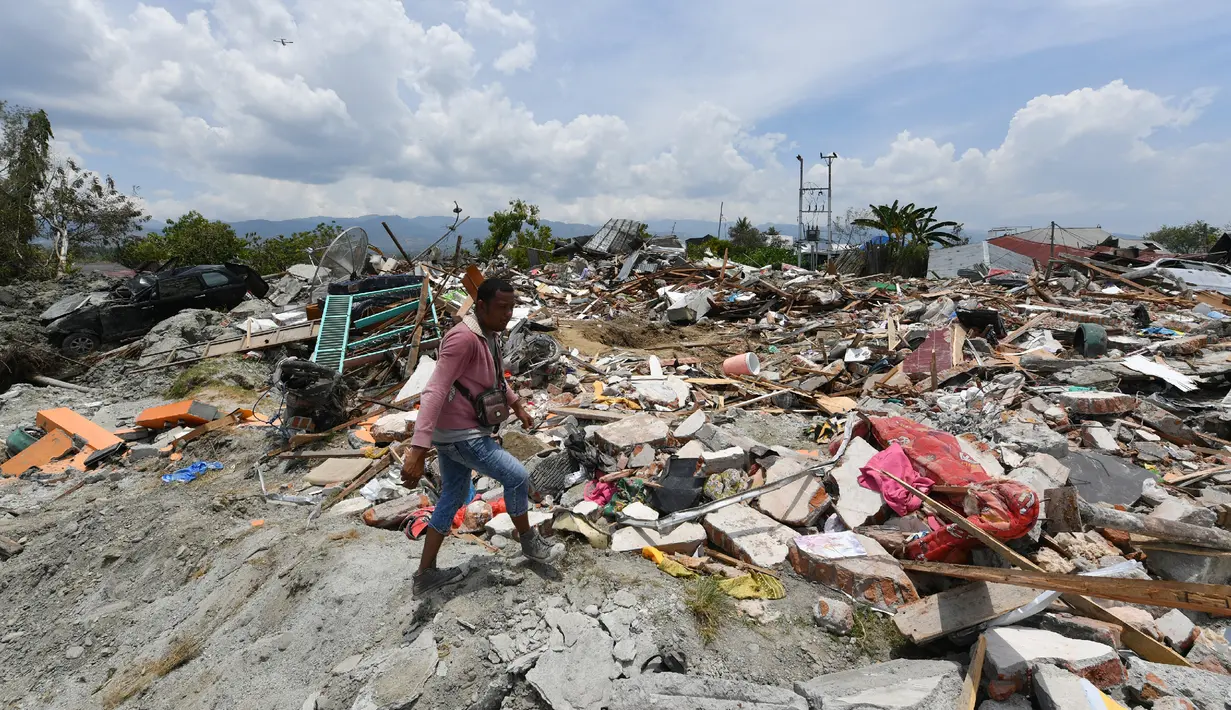 Seorang pria mencari barang yang tersisa di bangunan rumahnya yang hancur akibat gempa dan tsunami di Petobo, Palu, Kamis (4/10). Wilayah Kelurahan Petobo di Palu menjadi salah satu daerah yang terkena dampak parah karena 'ditelan bumi'. (AFP/ ADEK BERRY)