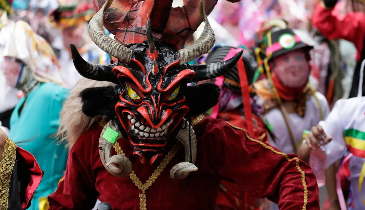 Orang-orang bersuka ria dalam balutan topeng setan selama festival  La Diablada di jalan-jalan kota Pillaro, Ekuador, Jumat (4/1). Anak-anak, pria, dan wanita memakai aneka pakaian menyeramkan menakut-nakuti orang-orang yang dilaluinya. (AP/Dolores Ochoa)