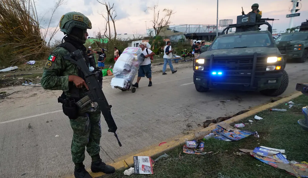 Tentara berjaga di jalanan sementara warga mengambil barang-barang dari toko-toko lokal setelah Badai Otis menerjang Acapulco, Meksiko, pada Kamis, 26 Oktober 2023. (AP Photo/Marco Ugarte)
