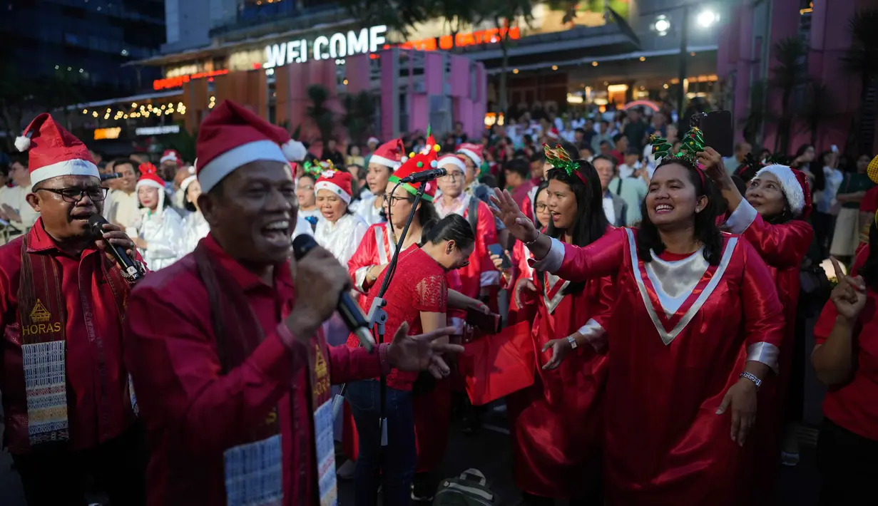 Peserta Christmas Carol menyanyi dengan mengenakan busana bernuansa Natal yang didominasi warna merah, hijau, dan putih. Tampak dalam foto, Umat Kristiani menyanyikan lagu-lagu Natal di Jakarta, Indonesia, Selasa, 23 Desember 2025. (AP Photo/Dita Alangkara)