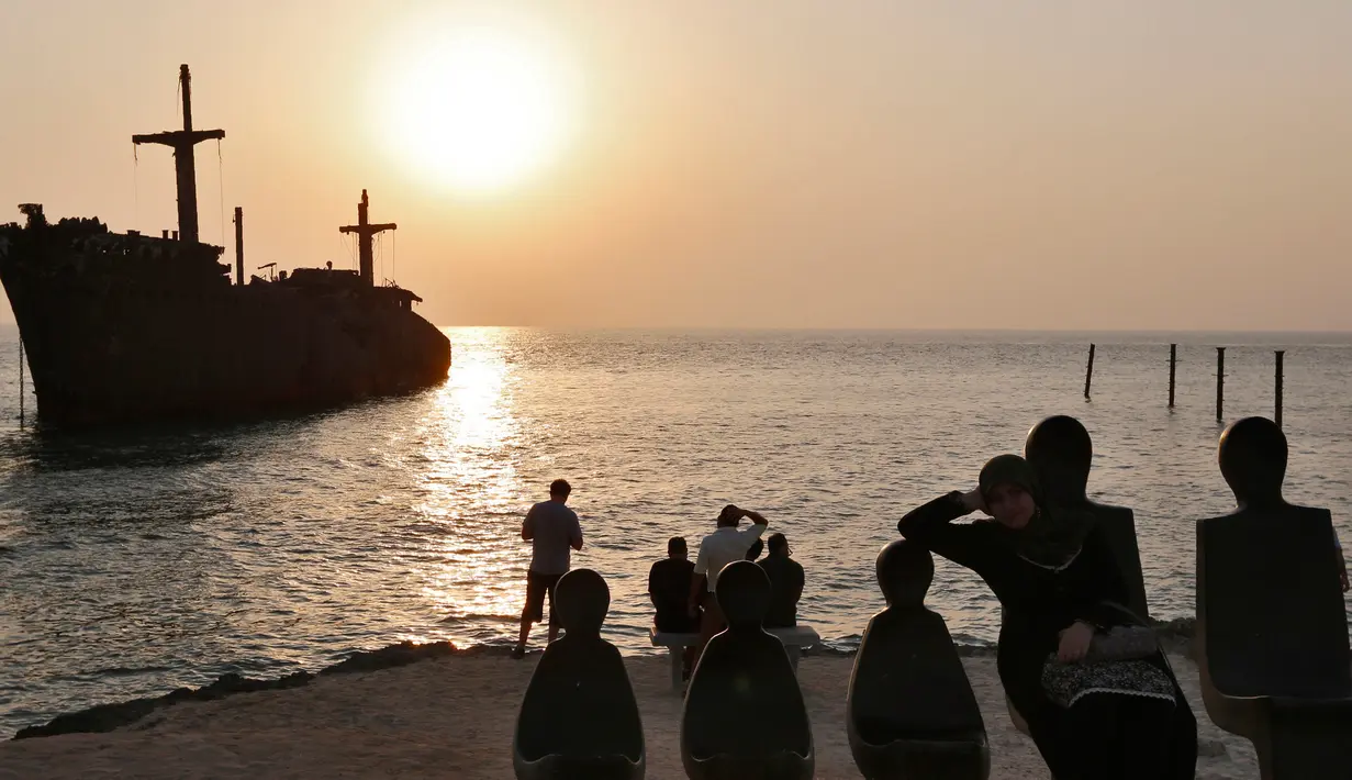 Sejumlah turis melihat matahari tenggelam atau sunset di pinggir laut, Pulau Kish, Iran, 1 November 2016. Iran sedang menjadi perbincangan di dunia wisata berkat upaya dari pemerintahan yang kembali menjalin hubungan dengan Barat. (Atta Kenare/AFP)