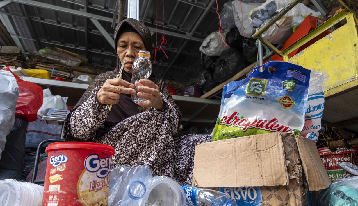 Seorang pegawai bank sampah memilah sampah anorganik rumah tangga, baik berupa karton maupun botol plastik, Jakarta, Kamis 4 Juni 2026, sebagai bagian dari instruksi Pemprov DKI yang mewajibkan warga memilih dan memilah sampah untuk mengurangi beban sampah yang semakin menumpuk di ibu kota. (BAY ISMOYO/AFP)