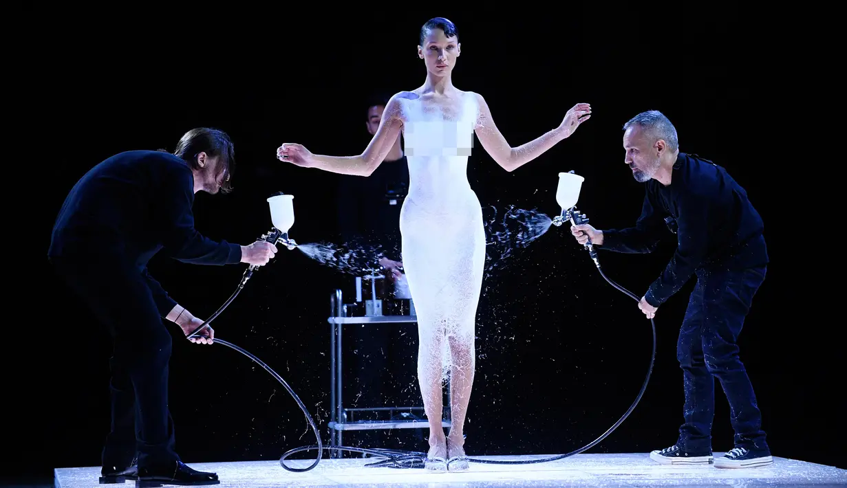 <p>Model AS Bella Hadid disemprot dengan cairan yang berubah menjadi gaun yang bisa dipakai saat peragaan busana Coperni Spring-Summer 2023 pada Paris Fashion Week di Paris, Prancis, 30 September 2022. Dihimpun dari Vogue, spray khusus itu terbuat dari Fabrican, bahan semprot yang mengeras menjadi tekstil sehingga bisa dipakai. (JULIEN DE ROSA/AFP)</p>