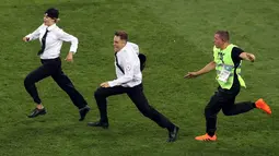 Petugas mengejar dua penyusup yang masuk ke lapangan dalam laga final Piala Dunia 2018 antara Prancis dan Kroasia di Luzhniki Stadium, Minggu (15/7). Pertandingan sempat dihentikan sebelum para penyusup ditangkap oleh petugas. (AP/Thanassis Stavrakis)