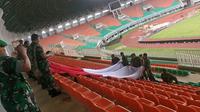 Anggota TNI dan suporter Timnas Indonesia tengah mencoba membentangkan Bendera Merah Putih di Stadion Pakansari, Kabupaten Bogor, Selasa (13/12/2016). (Bola.com/Istimewa)