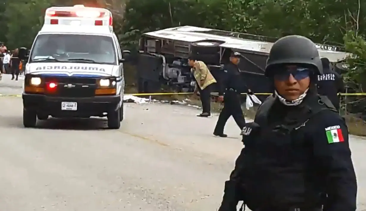 Petugas kepolisian berjaga di lokasi kecelakaan sebuah bus wisata yang terbalik di Quintana Roo, Meksiko, Selasa (19/12). Pihak berwenang belum mengeluarkan data resmi mengenai kewarganegaraan korban tewas. (Manuel Jesús ORTEGA CANCHE/AFP)