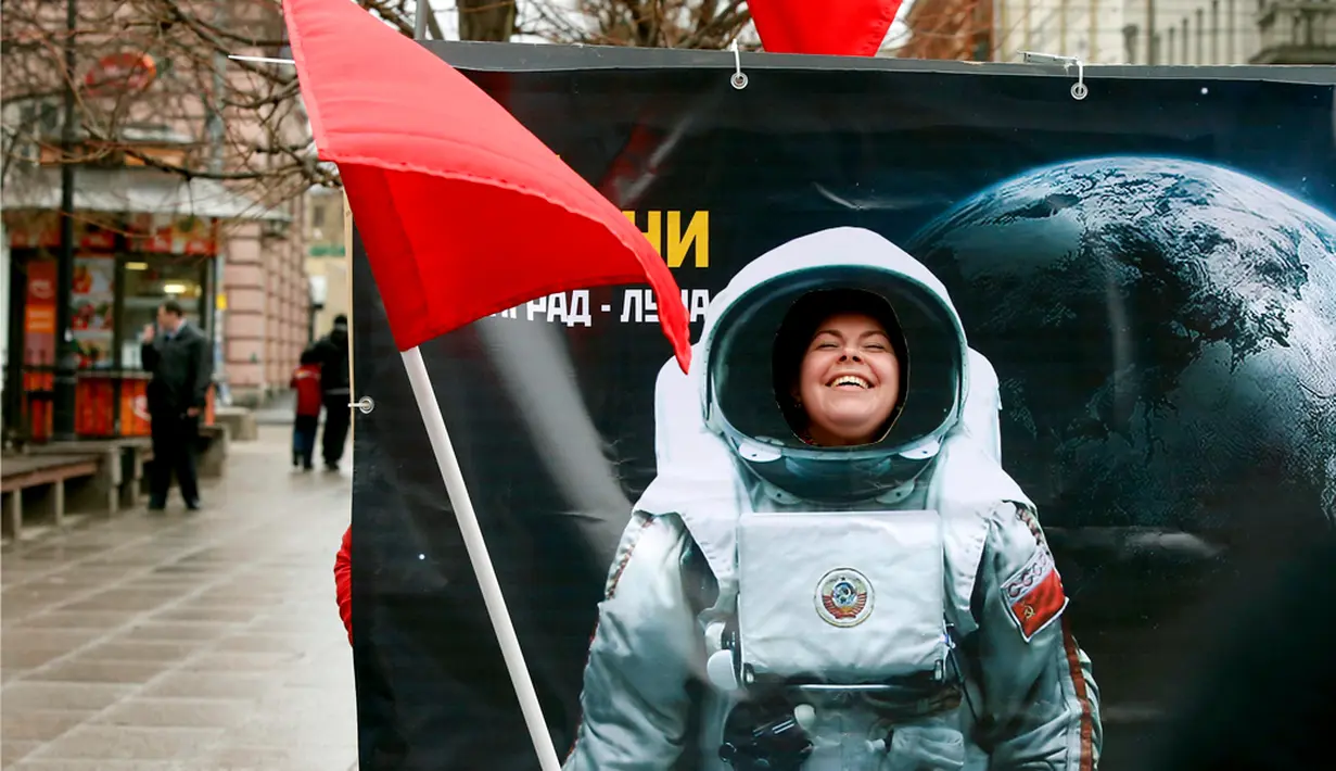 Seorang wanita tersenyum berpose di balik papan foto saat perayaan Cosmonautics Day di St Petersburg, Rusia pada Sabtu 12 April 2014.(REUTERS/Alexander Demianchuk)