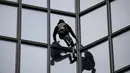Pendaki Alain Robert atau French Spiderman memanjat Menara Total di kawasan bisnis La Defense, Paris, Prancis, Senin (13/1/2020). Alain memanjat gedung 48 lantai tersebut sebagai dukungan untuk pekerja yang mogok karena menentang reformasi pensiun di Prancis. (Thomas SAMSON/AFP)