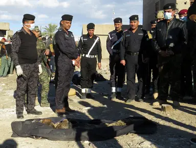 Polisi Irak berdiri di dekat jasad yang dieksekusi oleh kelompok ISIS di sebuah kuburan massal di Kota Ramadi, sebelah barat Baghdad, Selasa (26/1). Kuburan massal tersebut berisi sisa-sisa sekitar 40 jasad. (AFP/ MOADH AL-DULAIMI)