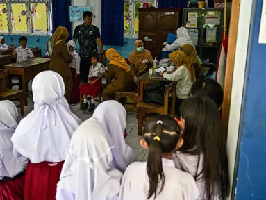 Para siswa menerima vaksin difteri di sebuah sekolah dasar di Surabaya, Jawa Timur pada Selasa 4 November 2025. Pelaksanaan program Bulan Imunisasi Anak Sekolah (BIAS) untuk tahun 2025 di Kota Surabaya, Jawa Timur dilaksanakan dalam dua tahap. (Juni KRISWANTO/AFP)