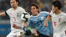 Striker Uruguay, Edinson Cavani berusaha melewati dua pemain Jepang, Takehiro Tomiyasu dan Gaku Shibasaki selama pertandingan grup C Copa America 2019 di Arena Gremio di Porto Alegre, Brasil (20/6/2019). Jepang bermain imbang 2-2 atas Uruguay. (AP Photo/Silvia Izquierdo)