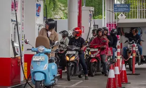 Kondisi ini turut mendorong penyesuaian harga bahan bakar minyak (BBM) secara global, termasuk Indonesia, secara bertahap. Tampak dalam foto, para pengendara sepeda motor mengantre untuk mengisi bahan bakar di sebuah Stasiun Pengisian Bahan Bakar Umum (SPBU) yang dioperasikan oleh Pertamina, perusahaan minyak dan gas milik negara Indonesia, di Yogyakarta, pada Sabtu 28 Maret 2026. (DEVI RAHMAN/AFP)
