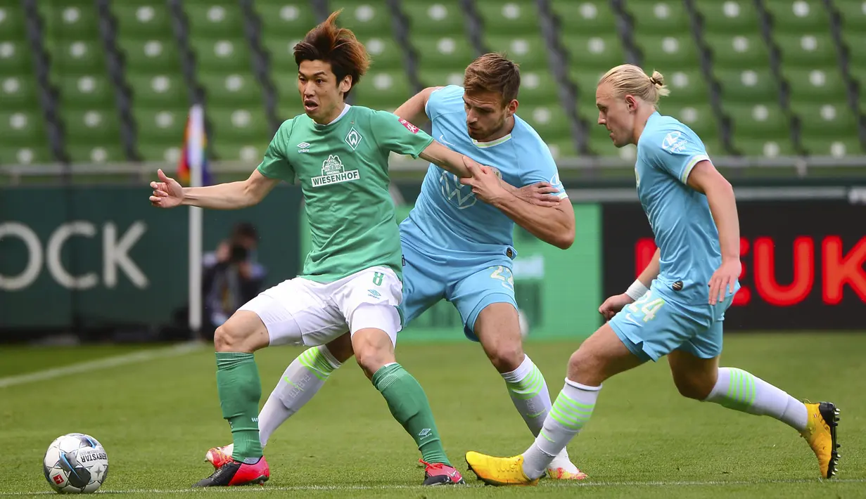 Pemain Werder Bremen, Yuya Osako, berebut bola dengan pemain Wolfsburg, Marin Pongracic, pada laga Bundesliga di Weserstadion Minggu (7/6/2020). Werder Bremen takluk 0-1 dari Wolfsburg. (AFP/Patrik Stollarz)