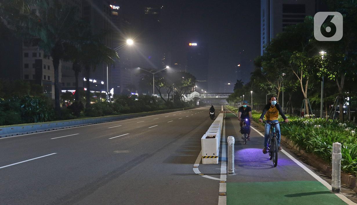 Warga bersepeda di jalan lengang kawasan Sudirman, Jakarta, Rabu (12/5/2021) malam. Polda Metro Jaya memberlakukan crowd free night untuk mencegah kerumunan takbir keliling di malam Idul Fitri 1442 yang berlaku mulai pukul 22:00 malam ini. (Liputan6.com/Herman Zakharia)
