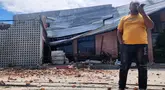 Seorang pria berbicara di telepon selulernya di dekat sebuah bangunan yang rusak akibat gempa di Palu, Sulawesi Tengah, Selasa 16 Juni 2026. (AP Photo/Josua Marunduh)