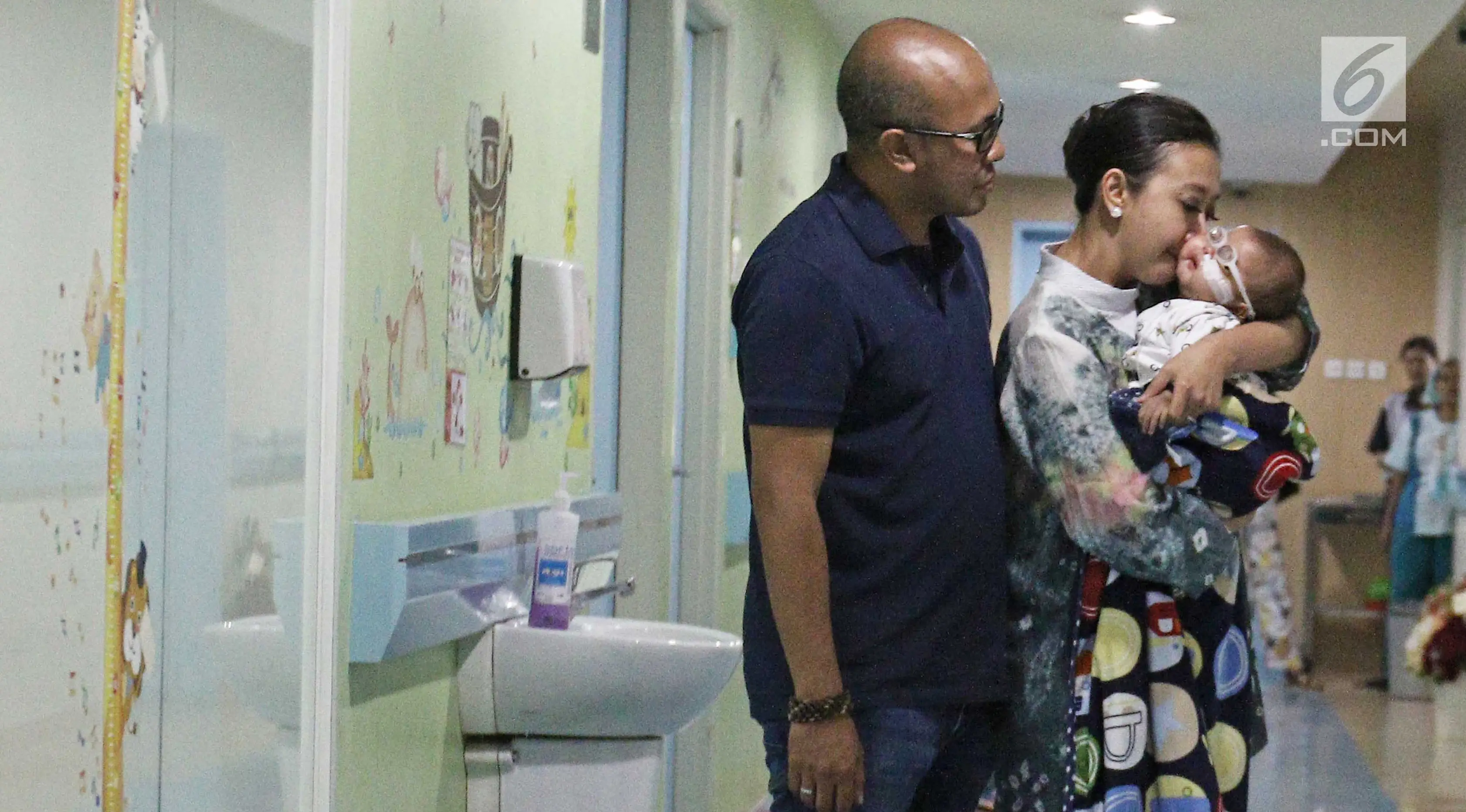 Artis Asri Welas bersama suami, Galiech Ridha Rahardja mencium kening anak kedua, Rayyan Gibran Ridha Rahardja usai jumpa pers di rumah sakit, Jakarta, Jumat (15/09). Ibran diizinkan pulang setelah menjalani operasi katarak. (Liputan6.com/Herman Zakharia)