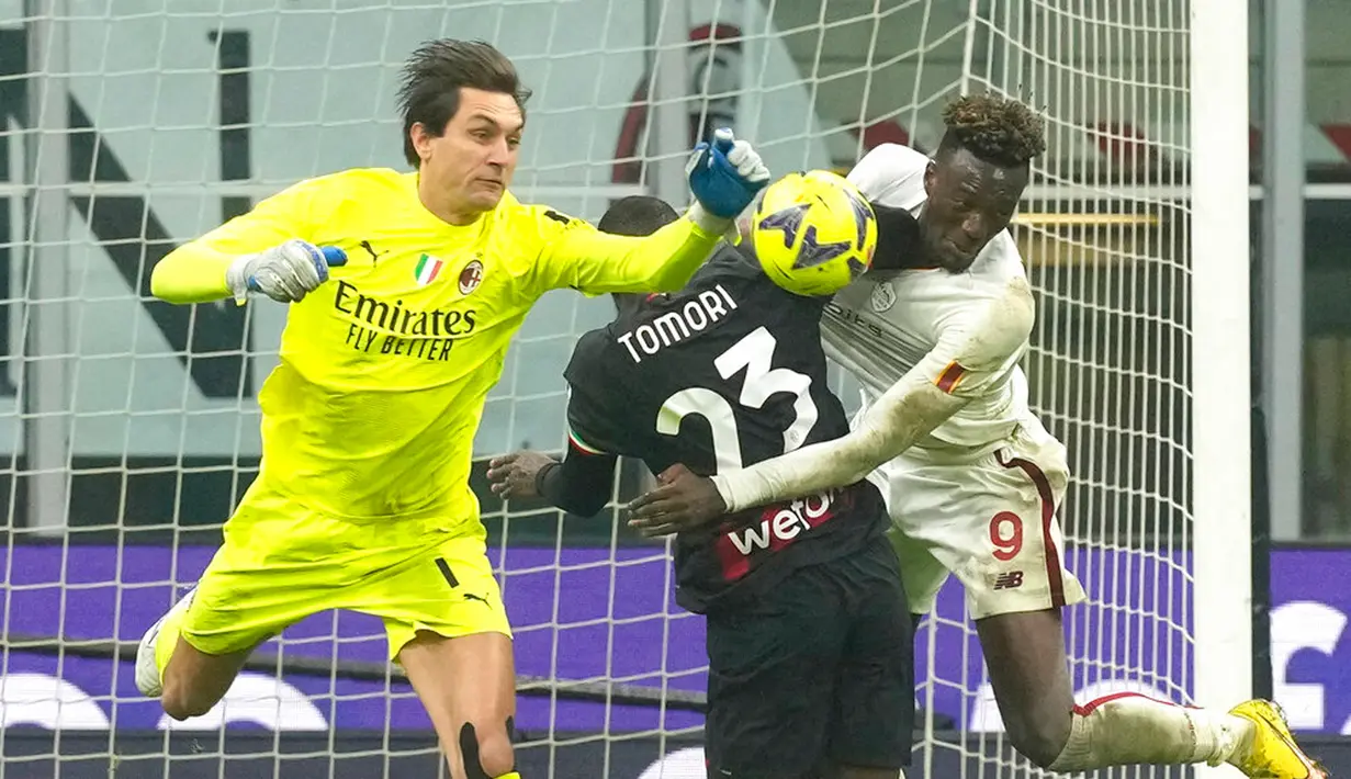 Kiper AC Milan Ciprian Tatarusanu meninju bola di bawah tekanan dari pemain AS Roma Tammy Abraham (kanan) pada pertandingan sepak bola Serie A Liga Italia di Stadion San Siro, Milan, Italia, 8 Januari 2023. Pertandingan berakhir imbang 2-2. (AP Photo/Antonio Calanni)