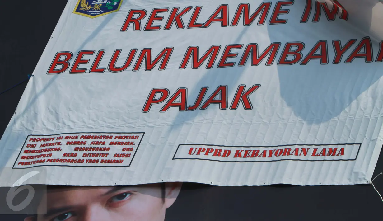 Sebuah reklame bergambar Dude Harlino tertutup spanduk di Kawasan Kebayoran Lama, Jakarta, Kamis (23/2). Reklame tersebut terkena razia oleh Satpol PP dan Dinas BP2T karena belum membayar pajak. (Liputan6.com/Gempur M Surya)