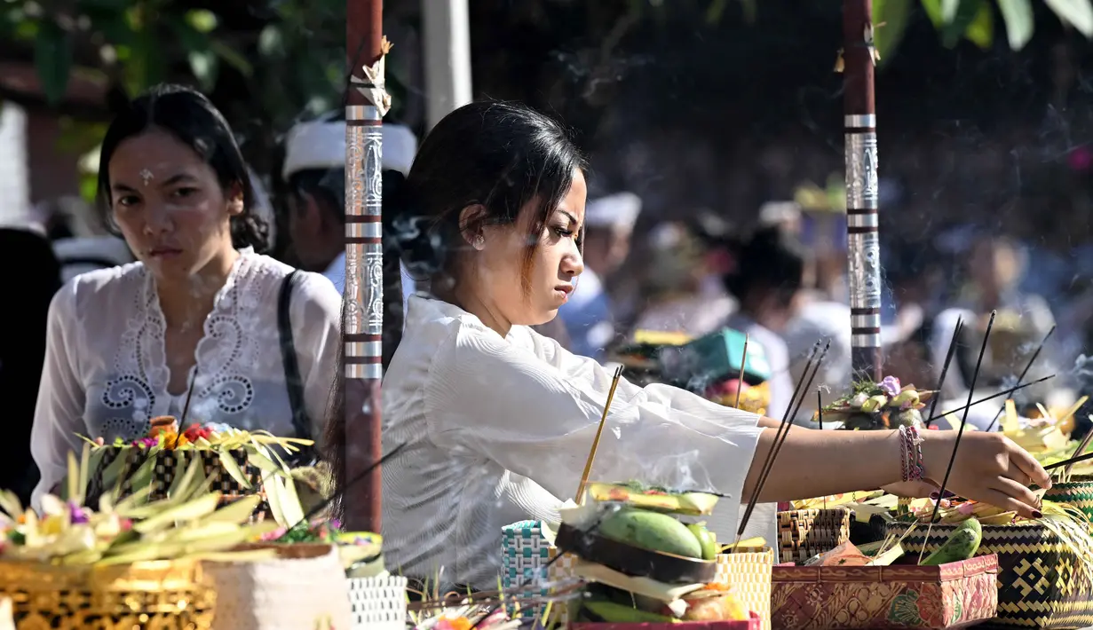Umat Hindu meletakkan persembahannya sebelum berdoa untuk merayakan Hari Raya Galungan di sebuah pura, Denpasar, Bali, Rabu 17 Juni 2026. (SONNY TUMBELAKA/AFP)
