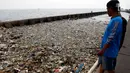 Warga mengamati sampah yang menutupi di pinggir laut kawasan Pelabuhan Muara Baru, Jakarta Utara, Senin (29/7/2019). Sampah-sampah yang didominasi oleh sampah plastik ini terbawa arus laut yang dibuang masyarakat secara sembarangan. (Liputan6.com/Johan Tallo)