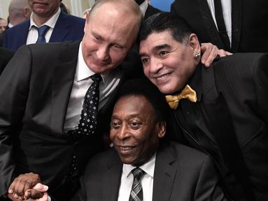 Legenda sepak bola, Diego Maradona dan Pele, foto bersama dengan Presiden Rusia, Vladimir Putin, saat menghadiri Drawing Piala Dunia 2018 di Kremlin Palace, Jumat (1/12/2017). Acara tersebut dihadiri legenda sepak bola dunia. (AFP/Alexey Nikolsky)