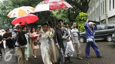 Sejumlah orang dari ormas islam memayungi sepasang mempelai yang akan melangsungkan pernikahan di Gereja Katedreal, Sabtu (11/2). (Liputan6.com/Herman Zakharia)