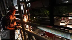 Petugas memotong kerangka besi dengan las ketika membongkar papan reklame di JPO Jalan Warung Buncit Raya, Jakarta, Jumat (7/10).  Adapun reklame itu dibongkar karena tidak berizin atau tidak sesuai syarat teknis reklame. (Liputan6.com/Helmi Afandi)