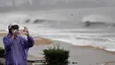 Badai juga berpotensi menyebabkan banjir di daerah dataran rendah. Tampak dalam foto, seorang warga merekam dengan ponselnya saat ombak menghantam Pantai Quy Nhon menjelang kedatangan Topan Kalmaegi di Provinsi Gia Lai, Vietnam Tengah, pada 6 November 2025. (NHAC NGUYEN/AFP)