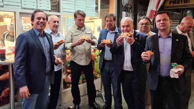 <span>Presiden Brasil Jair Bolsonaro bersama rombongan menyantap pizza sebagai makan malam di trotoar jalan New York, Amerika Serikat (AS). (dok. Twitter @MinLuizRamos)</span>