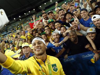 Bintang sepak bola Brasil, Neymar, berfoto bersama pendukungnya setelah meraih emas sepak bola Olimpiade Rio 2016 setelah mengalahkan Jerman di final, (20/8/2016). (AFP/Odd Andersen)