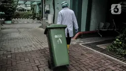 Petugas membawa tong sampah berisi limbah Covid-19 di Tempat Penyimpanan Sementara Limbah B3 di Labkesda DKI Jakarta, Selasa (4/8/2020). Pembuangan limbah Covid-19 di Labkesda DKI Jakarta dilakukan dengan proses ketat sesuai protokol kesehatan. (merdeka.com/Iqbal Nugroho)