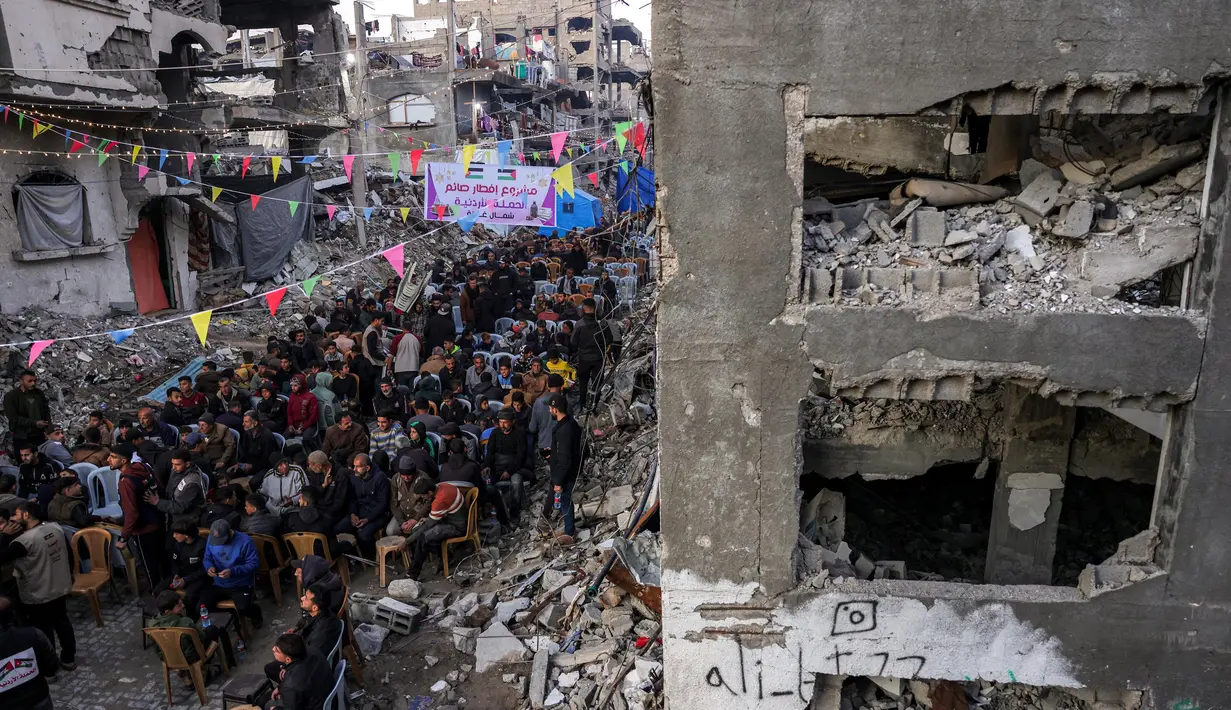 Mereka terpaksa berbuka puasa di sekitar reruntuhan bangunan permukiman yang runtuh akibat perang antara Israel dan Hamas. (Bashar TALEB/AFP)