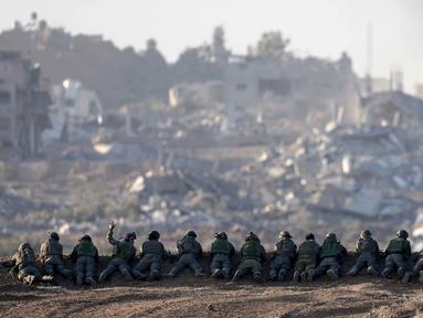 Sebuah foto yang diambil di Israel selatan dekat perbatasan dengan Jalur Gaza pada 11 Desember 2023, menunjukkan tentara Israel berjaga di sebuah bukit yang menghadap ke Gaza utara, di tengah pertempuran yang terus berlanjut antara Israel dan kelompok militan Hamas. (Menahem KAHANA/AFP)