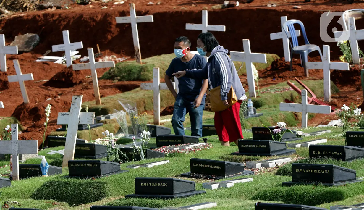 Warga mencari makam kerabatnya di area pemakaman khusus dengan protokol COVID-19 di TPU Pondok Ranggon, Jakarta, Jumat (25/12/2020). Momen perayaan Natal 2020 dimanfaatkan umat kristiani untuk berziarah mendoakan kerabat yang dimakamkan dengan protokol COVID-19. (Liputan6.com/Helmi Fithriansyah)
