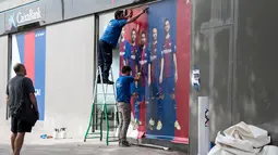 Pekerja memasang poster baru di luar Stadion Camp Nou di Barcelona (2/8). Pesepakbola 25 tahun ini akan menjadi pemain termahal di dunia dengan transfer 222 juta euro dari Barcelona ke PSG. (AFP Photo/Josep Lago)