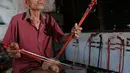 Ghohyong memainkan alat musik Tehyan khas Tionghoa buatannya di Neglasari, Kota Tangerang (5/2/2021). Akibat pandemi Covid-19 membuat pria tua tersebut tidak menerima orderan pembuatan alat musik Tehyan.  (Liputan6.com/Angga Yuniar)