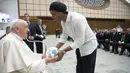 Mantan pesepak bola Brasil, Ronaldinho memberikan bola kepada Paus Fransiskus saat menghadiri audiensi dengan peserta pertandingan penghormatan "match for peace" untuk mengenang mendiang pemain Argentina, Diego Maradona, pada 14 November 2022 di aula Paul-VI, Vatikan. Pertandingan ini diselenggarakan oleh "WePlayForPeace", sebuah yayasan yang didirikan oleh Paus Fransiskus. (AFP/Vatican Media)