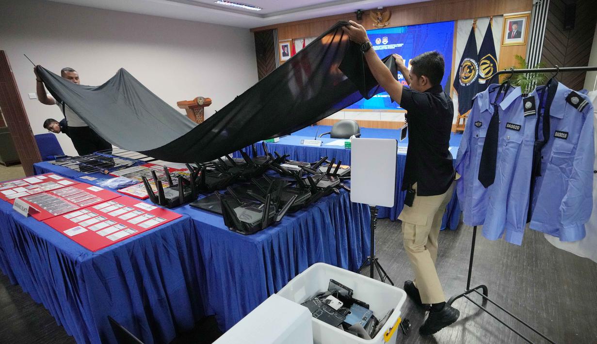 Mereka diringkus di kawasan Babakan Madang, Kabupaten Bogor, karena diduga menyalahgunakan izin tinggal dan diduga menjalankan praktik online scam atau penipuan daring. Tampak dalam foto, petugas Imigrasi menutupi barang bukti yang disita dari warga negara Jepang yang diduga terlibat dalam sindikat penipuan daring (online), di Bogor, Jawa Barat, Rabu 4 Maret 2026. (AP Photo/Achmad Ibrahim)