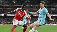 Bukayo Saka mencoba menggocek pemain Burnley. (Glyn KIRK / AFP)